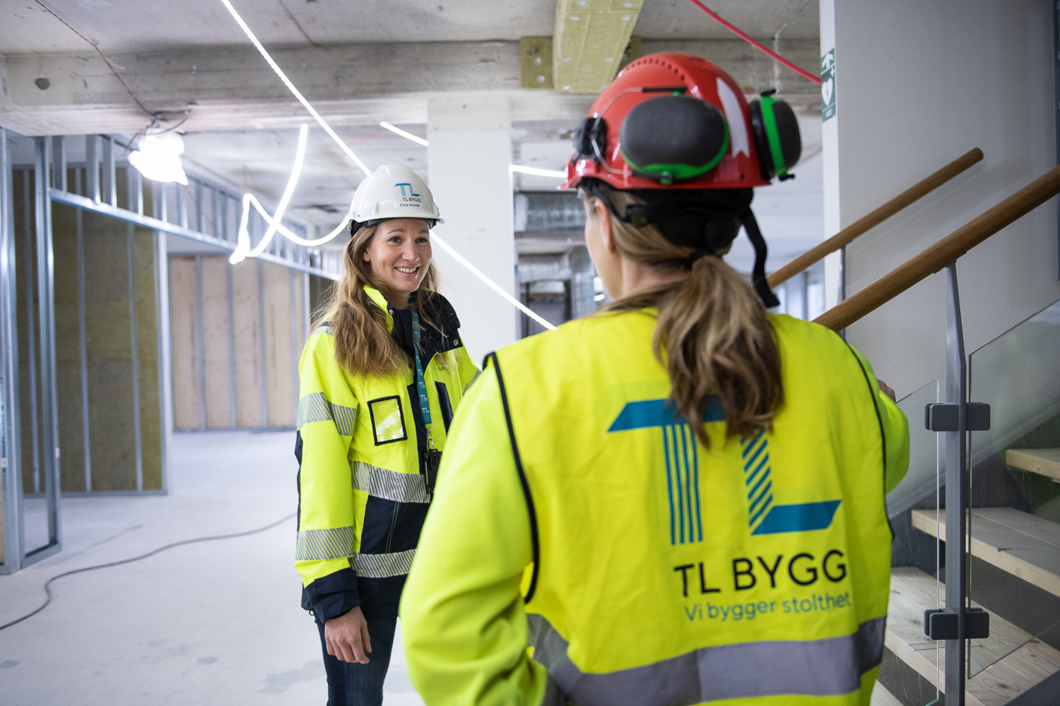 tva kvinnliga byggarbetare pratar en byggarbetsplats